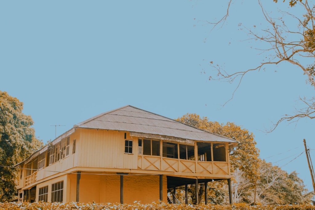 a yellow house sitting on top of a lush green hillside